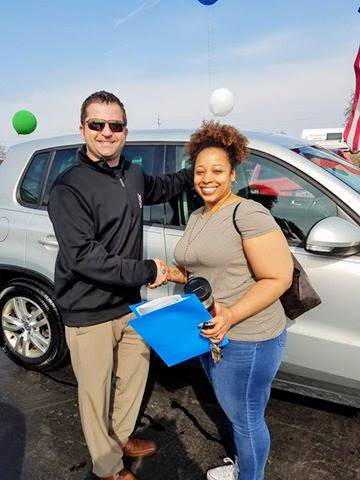 Happy Woman Holding Paperwork With New Car and Sales Person